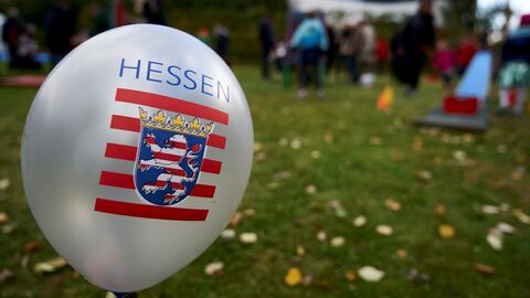 Hessen steigen lassen Ein Luftballon mit Hessenwappen vor einer Wiese.