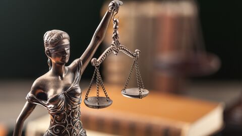Justizia-Statue vor einem Bücherstapel Justizia-Statue vor einem Bücherstapel