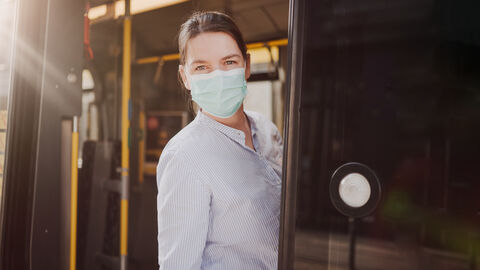 Eine Frau mit Maske steht in der Tür eines Busses Eine Frau mit Maske steht in der Tür eines Busses