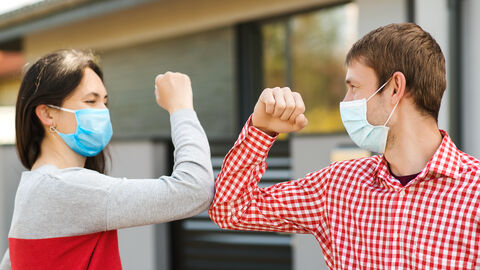Corona-Gruß Eine Frau und ein Mann mit Maske grüßen sich per Ellenbogen