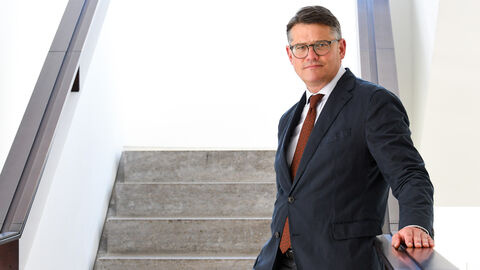 Boris Rhein Boris Rhein steht auf einer Treppe, an das Treppengeländer angelehnt.
