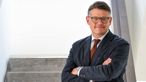 Boris Rhein Boris Rhein steht mit verschränkten Armen auf einer Treppe.