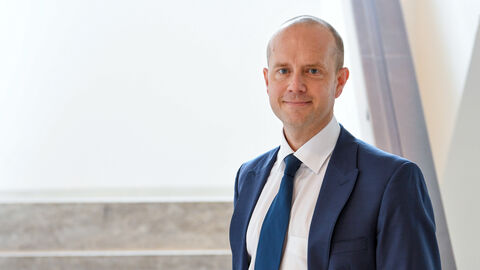 Regierungssprecher Tobias Rösmann Regierungssprecher Tobias Rösmann im Porträt vor einer Treppe, er lächelt in die Kamera.
